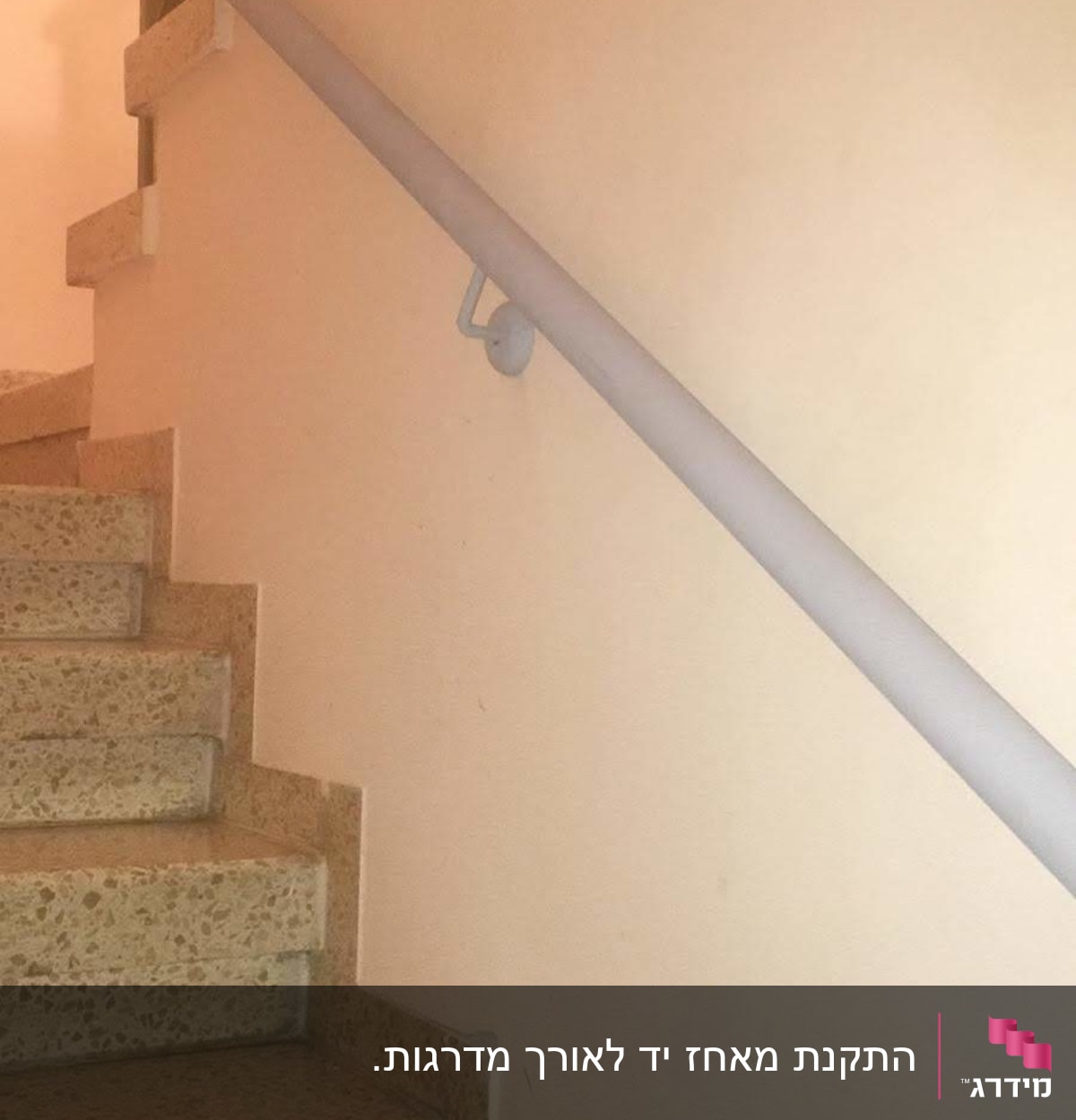 מעקה מתכת צמוד לקיר מעל מדרגות אבן